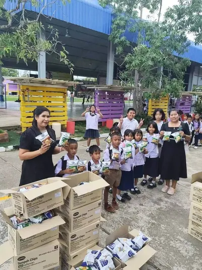 นักเรียนโรงเรียนประถมศึกษารับขนมเทมเป้ทอดกรอบที่วัดจุฬามณีมอบให้