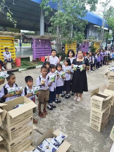 นักเรียนโรงเรียนประถมศึกษารับขนมเทมเป้ทอดกรอบที่วัดจุฬามณีมอบให้