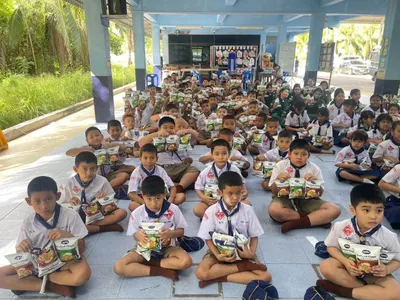 นักเรียนโรงเรียนประถมศึกษารับขนมเทมเป้ทอดกรอบที่วัดจุฬามณีมอบให้